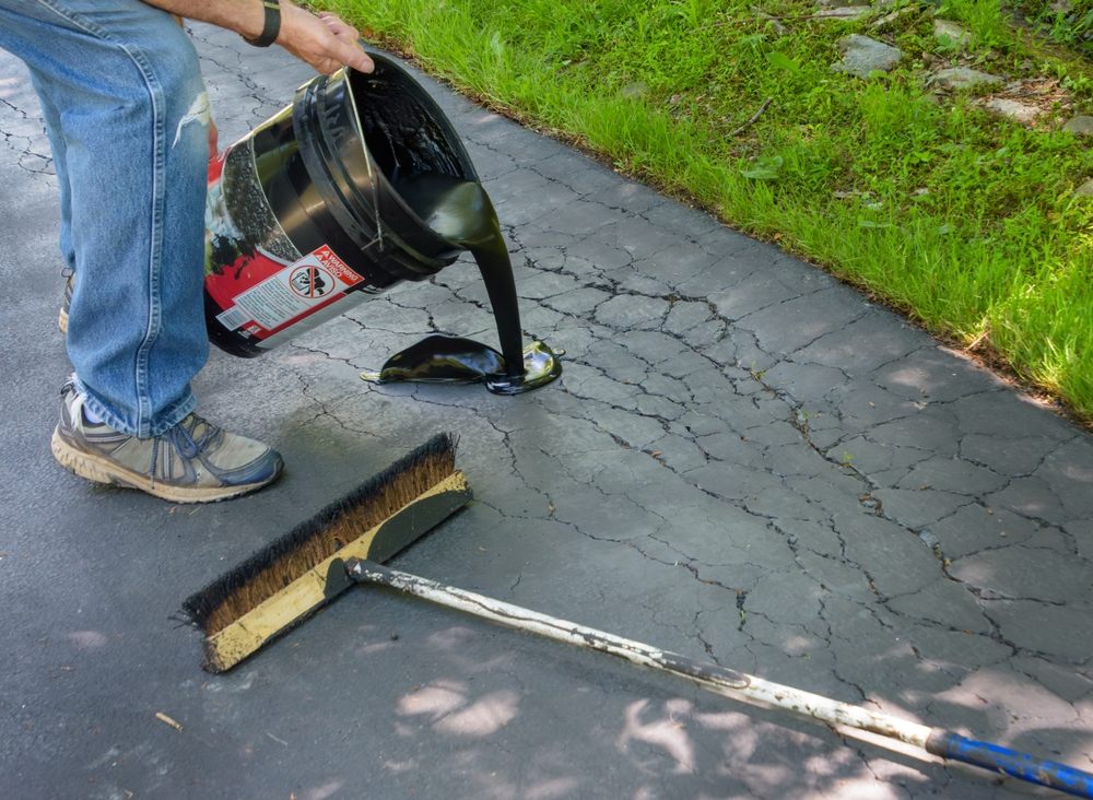 Why Asphalt Maintenance Matters: Protecting Your Driveway & Saving Money. Pouring asphalt sealant on the driveway to repair cracks.