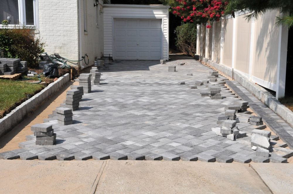 5 Ways Interlock & Landscaping Boost Curb Appeal & Property Value. Workers are installing a new interlock in the driveway.