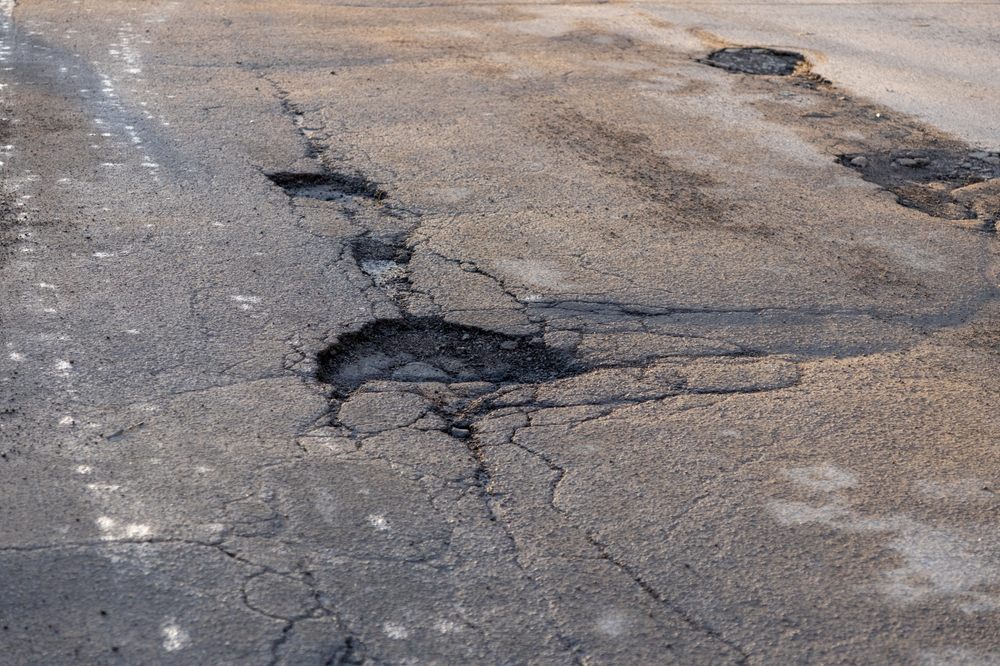 How to Choose the Right Asphalt Repair Service for Your Ottawa Home. potholes in the road, holes in the asphalt on the roadway or highway. road surface repair work.